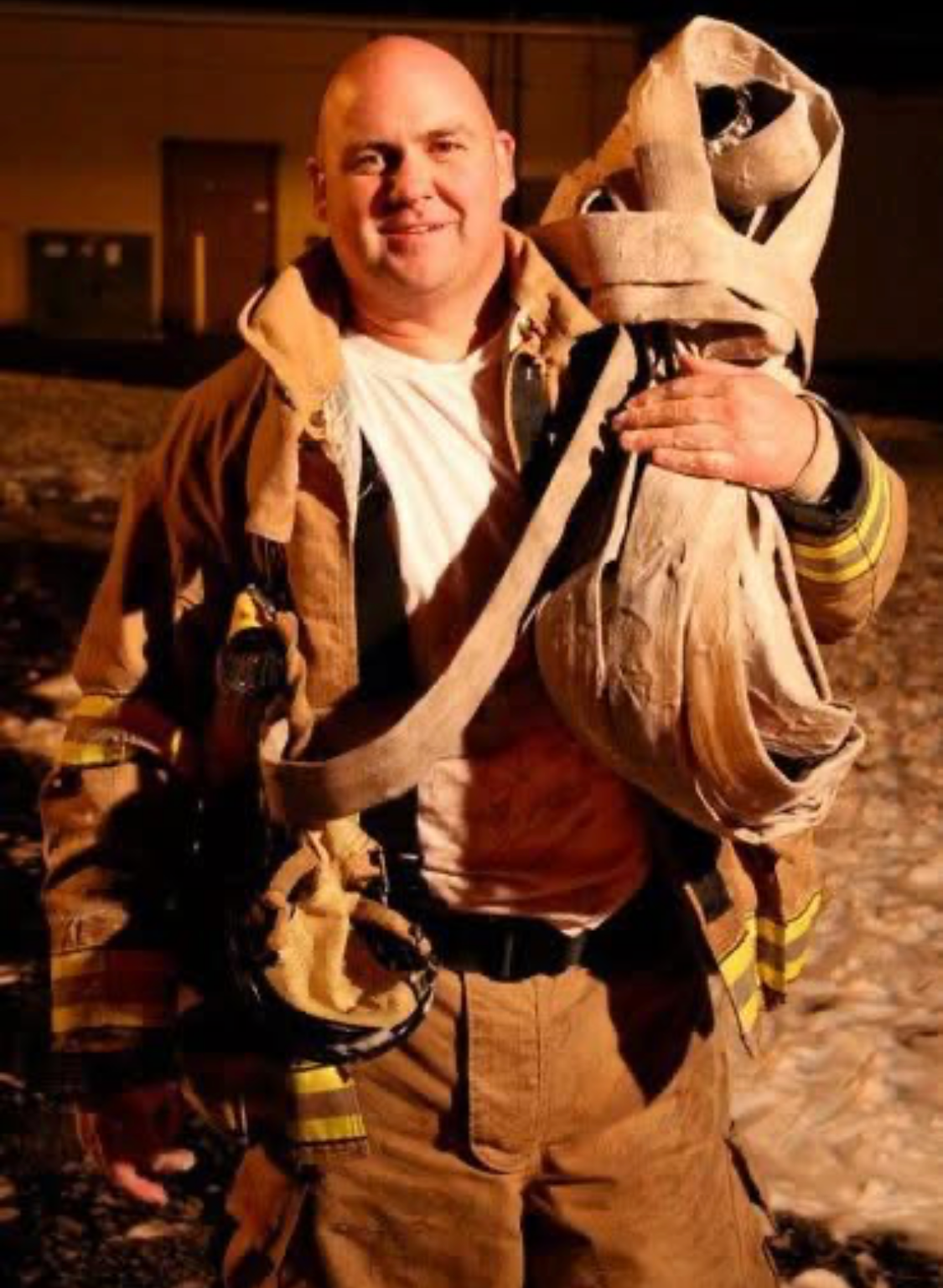 Firefighter in turnout gear carrying hose